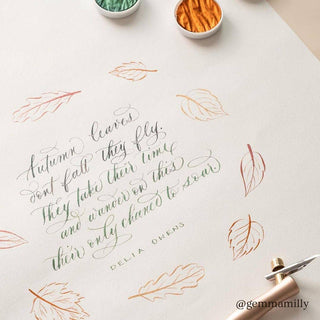 A handwritten autumn-inspired quote with colorful leaf sketches around it, calligraphy pens, and thread spools on a light surface. The quote is by Delia Owens and credited to @gemmamilly.