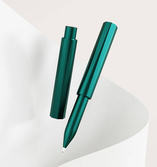 The Wren - Refillable Writing Pen is displayed on a white, curved paper background. Its metallic green, hexagonal body and Japanese-made writing tip create a modern, sleek look. The pen features a removable cap for convenience.