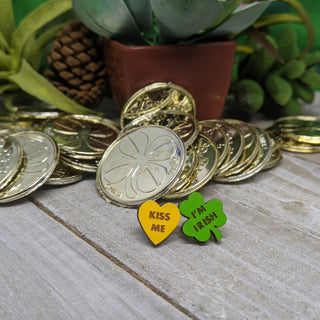 Gold coins and a potted succulent accent Saint Patrick’s Day with two pins: a yellow heart labeled "Kiss Me" and a green shamrock reading "I’m Irish," matching the handmade Kiss Me I’m Irish Earrings for St. Patrick’s Day, made in the USA.