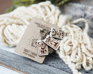 🔮 Tarot Card Stitch Markers– The Tower, The Devil & Judgement 🔮: Detailed maple wood stitch markers and knitting progress keepers displayed on a labeled card atop cream yarn. Perfect crochet accessories for fiber artists.