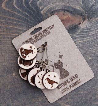 The Witching Hour Stitch Markers from SUNRISE GROVE KNITTERY feature maple wood charms—a hat, broom, and cat—making them the perfect witch-themed knitting accessory.