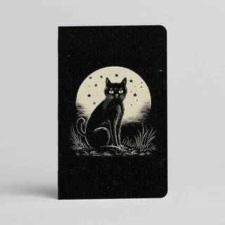 The cover of the 🌙 Moonlit Cat Notebook 🐈‍⬛ features a black cat on grass beneath a starry full moon, handmade in Austin.