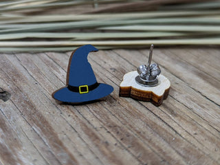 A small witch hat & cat earring with a blue brim and yellow buckle, displayed by its backing on rustic wood with dried grass—perfect handmade Halloween earrings for any witch hat & cat earring lover.
