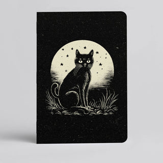 The 🌙 Moonlit Cat Notebook 🐈‍⬛ is a handmade pocket notebook from Austin, featuring a black cat on grass under a glowing full moon and stars in the night sky.