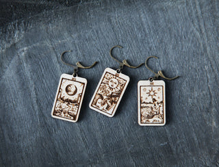 The 🔮 Tarot Card Stitch Markers – The Moon, The Star & The Sun 🔮 feature three rectangular earrings, each with a unique tarot card design—ideal as progress keepers or stitch markers for your knitting accessories collection.