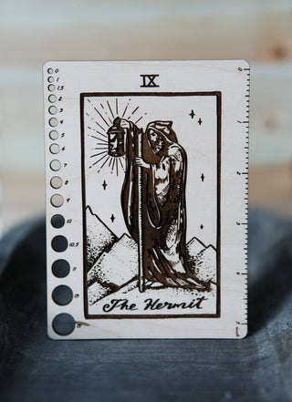 The ✨ The Hermit ✨ Tarot Knitting Needle Gauge & Ruler features a maple wood design of The Hermit with lantern, plus rulers and circular guides—an enchanting tarot-inspired tool for knitters.