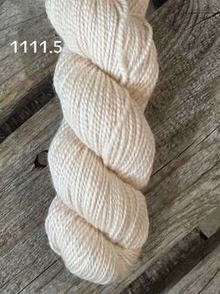 A skein from the KPM and KPPPM Variegated Color Collection rests coiled on a rustic wooden surface, with “1111.5” in white text above—perfect for your next hand knitting project.