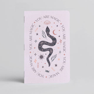 The ✨ You Are Magic Notebook ✨ is a pastel pink handmade pocket notebook from Austin, featuring a dark snake, stars, crescent moon, leaves, and the phrase YOU ARE MAGIC encircling the magical design.