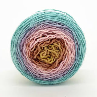 A round skein of Freia Ombre & Gradient Sport Wool Yarn viewed from above shows concentric layers of teal, lavender, brown, pink, and yellow against a plain white background.