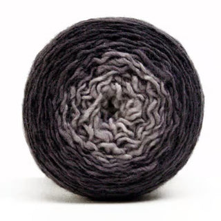The Freia Ombre & Gradient Sport Wool Yarn is a round cake featuring a gradient that shifts from light gray at the center to dark gray at the edge, shown against a white background.