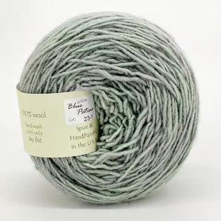A ball of Freia Semi-Solid Sport Wool Yarn in Blue Patina (lot 231)—heavy sport weight, 100% US Columbia Corriedale Rambouillet wool, handwash cool, dry flat; spun and handpainted in the USA. Light green & grey.