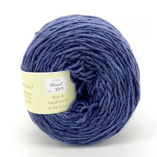 A ball of Freia Semi-Solid Sport Wool Yarn in blue, labeled "Diesel," with a cream-colored band. This DK weight, 100% US wool yarn is spun and hand-painted in the USA.