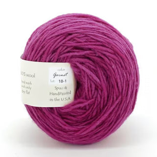 A ball of Freia Semi-Solid Sport Wool Yarn in Garnet, magenta US sport weight, spun and hand-painted in the USA, includes care instructions on a white tag wrapped around the skein.