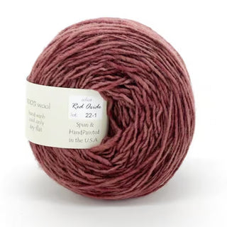 A ball of Freia Semi-Solid Sport Wool Yarn in Red Oxide, labeled 100% US wool, hand wash only, hand-painted, sport weight, spun in the USA, with a white tag.