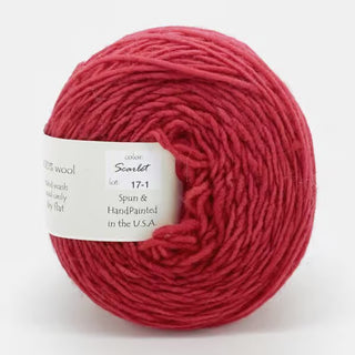 A ball of Freia Semi-Solid Sport Wool Yarn in Scarlet, made from 100% US wool. Spun and hand-painted in the USA. Label advises hand wash and lay flat to dry.