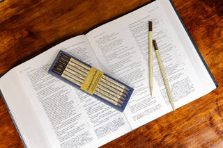 Open book with a set of pencils on a wooden surface