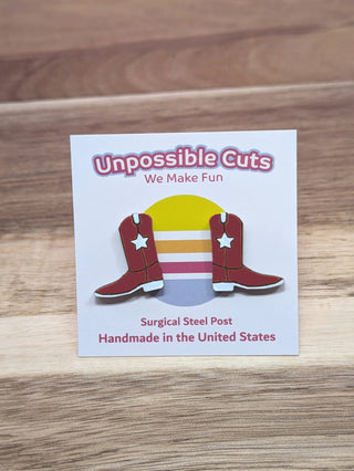 Two maroon cowboy boot-shaped earrings with white stars are displayed on a rainbow card reading "Cowboy Boots Handmade Earrings"—handmade in the United States, perfect for lovers of unique jewelry.