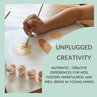 A child uses the Smiley Sunshine Paint-by-Number Kit for Kids, creating vibrant shapes on paper. Nearby, paper flowers brighten the scene. Unplugged Creativity—screen-free art sparks mindfulness and nurtures young minds.