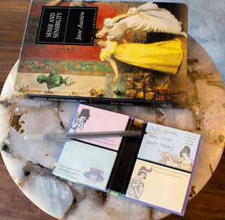 A set of Jane Austen Sticky Notes lies on a marble table beside a copy of Sense and Sensibility and a pen; one note says, Ask Emma for more book recs.