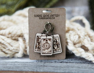 The 🔮 Tarot Card Stitch Markers – Justice, Wheel of Fortune & The Chariot 🔮 set features maple wood progress keepers on a Sunrise Grove Knittery card—ideal as crochet accessories or knitting stitch markers. Cream yarn shown for inspiration.