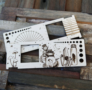 The Apothecary "Almost Everything" Ruler includes two wooden templates with engraved measurement scales, geometric and nature-themed designs—such as mushrooms, cacti, crystals, and a moon—plus a convenient knitting gauge.