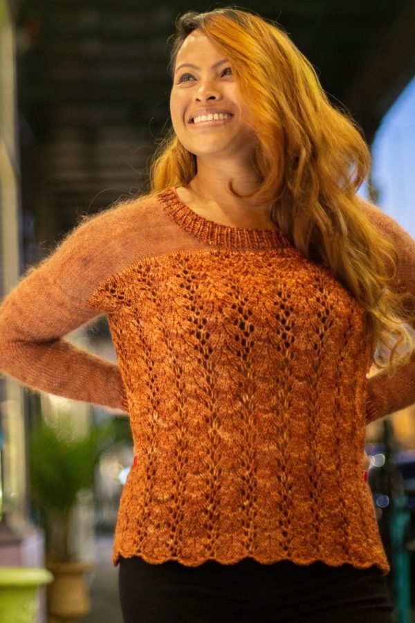 Beautiful woman wearing a deep orange sweater with light mohair sleeves and a lacy DK knit bottom.