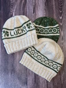 Image of three knit hats. One shows the front of the My Lucky Hat design, while the other two show the back.