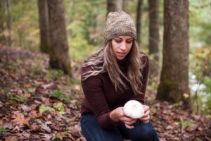 Women wearing knit hat with no pom pom while holding a mushroom outside