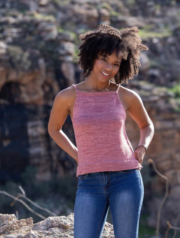 Light skinned Black woman modeling a pink knitted tank top and jeans; ajo tank knitting pattern in Nomadic Knits creative knitting magazine, colorway by indie yarn dyer Spirit Trail Fiberworks