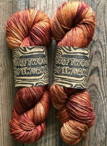 two twisted hanks of yarn in a pretty rose gold tonal yarn; the colorway was used on the Beautifully Basic henley knitting pattern found in nomadic knits knitting magazine subscription