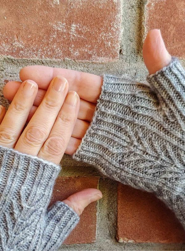 two hands wearing grey fingerless mitts, designed by Kate Atherley and knit using a soft grey from a Michigan indie yarn dyer; pattern available in Nomadic Knits creative knitting magazine